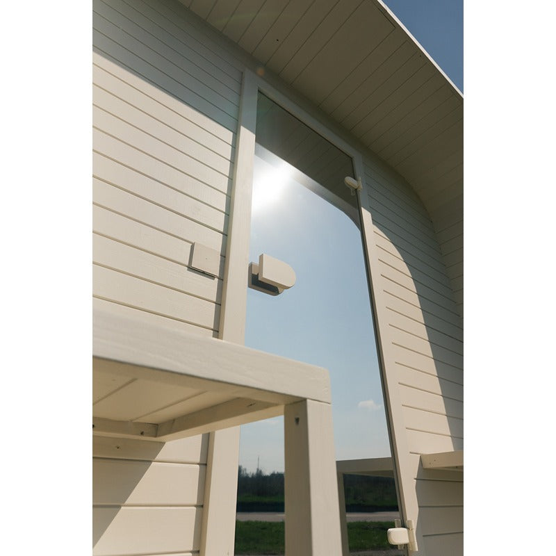 Exterior view of the Ula Large sauna with glass door and light wood cladding in the sunlight